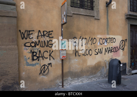 Graffiti politici spruzzata tramite aerosol su edificio pubblico vicino al Ponte Vecchio a Firenze. Foto Stock