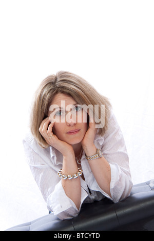 Triste donna in studio appoggiata sul banco di lavoro con testa in mani Foto Stock