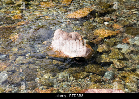 Rocce e ciottoli sul letto del fiume Esk visto attraverso il pattern di acqua dell'acqua chiara Eskdale Cumbria Inghilterra England Foto Stock