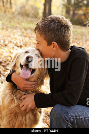 Ritratto di felice ragazzo baciare il suo golden retriever cane al parco Foto Stock