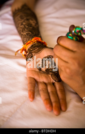 Una giovane sposa indiana giace sul suo letto come ella ha henna decorato sul suo braccio e Palm da un artista locale, come lei inizia preparati Foto Stock