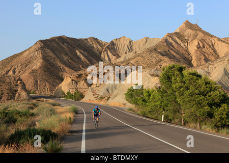 Ciclista pedalando attraverso il deserto Tabernas in Andalusia, Spagna Foto Stock