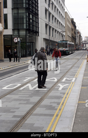 Pedoni e ciclisti sul tram Metrolink via nel centro della città di Manchester UK. fotografia DON TONGE Foto Stock