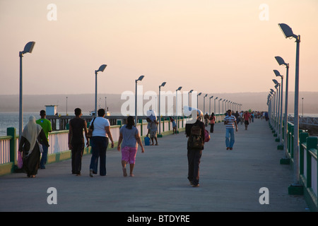 Un mix di turisti e di gente del posto a piedi lungo il molo al Inhambane Foto Stock