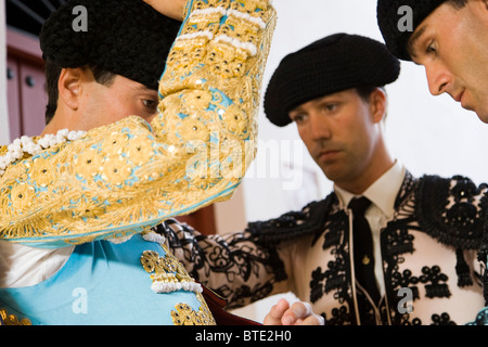 Assistenti aiutando il torero messo sul suo abbigliamento, Siviglia, Spagna Foto Stock