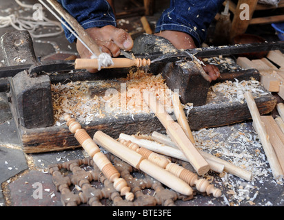 Un artigiano scolpisce articoli di legno con un tornio utilizzando i suoi piedi in un souk di Marrakech. Foto Stock