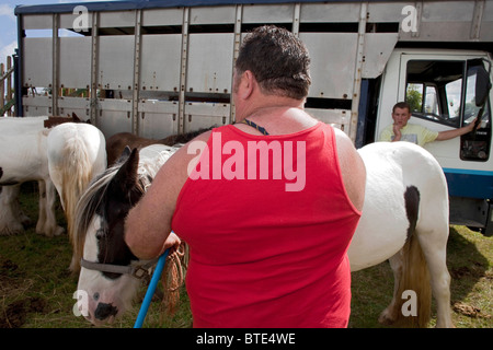 Un grande forte gypsy uomo che indossa un gilet rosso, sorge con la schiena rivolta verso di noi i suoi cavalli al Priddy ovini Fair DAVID MANSELL Foto Stock