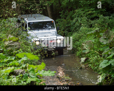 Argento Land Rover Defender guida attraverso un ruscello del Domaine d'Arthey estate in Belgio Foto Stock