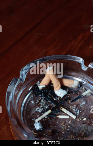 Stubbed fuori delle sigarette in un posacenere con vecchie corrispondenze Foto Stock