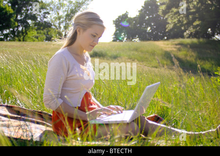 Giovane donna utilizzando il computer portatile in posizione di parcheggio Foto Stock