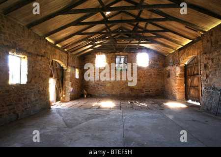 Interno di un fienile costruito in pietra con un ferro corrugato tetto Foto Stock