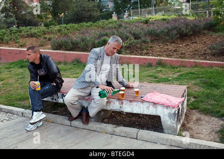 Un uomo si versa la birra in un parco a Tirana, la capitale dell'Albania. Foto Stock