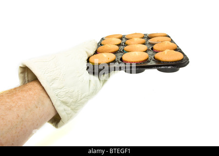 Mano indossando forno mit tenendo il vassoio a caldo di cucinate fresche e torte di coppa. Foto Stock