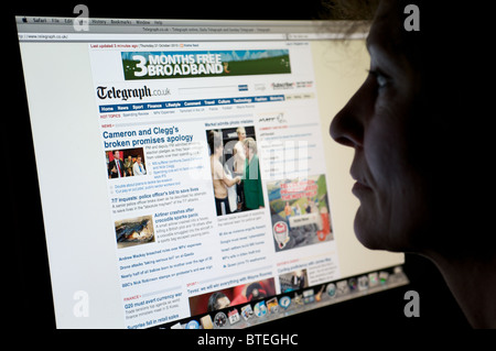 La donna la lettura di un Daily Telegraph edizione on-line Foto Stock