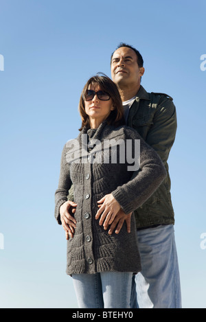 Matura in piedi insieme all'aperto, uomo abbracciando la donna da dietro Foto Stock