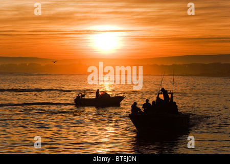 Barca da pesca stagliano in inizio di mattina di sunrise e come teste fuori in mare Foto Stock