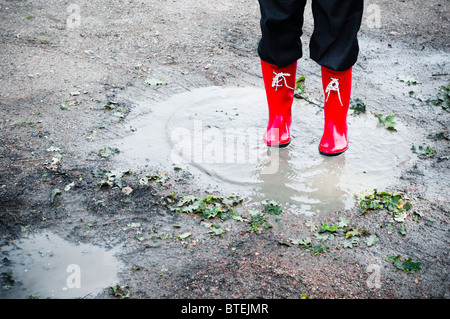 Woman in Red wellingtons in piedi in una pozza Foto Stock