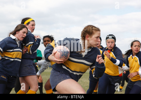 Un George Washington University il giocatore porta la palla contro Navy durante una donna partita di rugby. Foto Stock