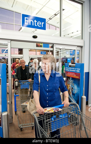 Maschio e femmina seniors vuoto spingere carrelli di shopping attraverso l ingresso di nuovi Walmart durante il negozio di grande apertura di Austin in Texas Foto Stock