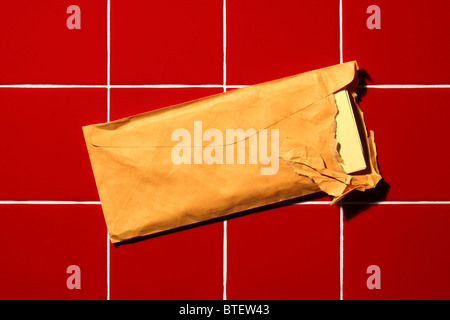 Un usato mailing postale busta strappata aperta. Rosso sfondo piastrellato Foto Stock
