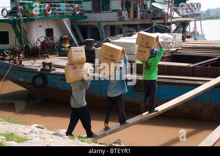 Operai cinesi sono il caricamento di una imbarcazione cargo con scatole di merci sul fiume Mekong in Chiang Sean, Thailandia. Foto Stock