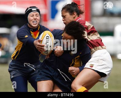 Navy sfera portante è affrontato da una università di Norwich giocatore durante una donna corrisponde all'annuale Cherry Blossom torneo di Rugby Foto Stock