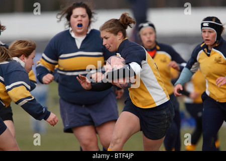 Un accademia navale il giocatore porta la palla durante una donna partita di rugby contro la George Washington University. Foto Stock