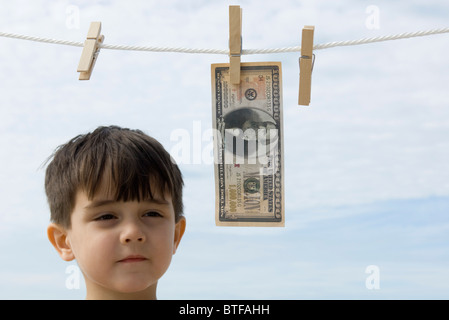 Ragazzo contemplando un milione di dollaro appeso su vestiti-line Foto Stock