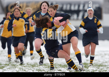 Un accademia navale di supporto a sfera collide con un George Washington University avversario durante un snowy donna partita di rugby. Foto Stock