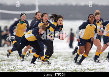 Un George Washington University il giocatore porta la palla contro l'Accademia Navale durante una snowy donna partita di rugby. Foto Stock