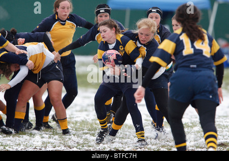 Un George Washington University player è affrontato da un'Accademia Navale avversario durante un snowy donna partita di rugby. Foto Stock