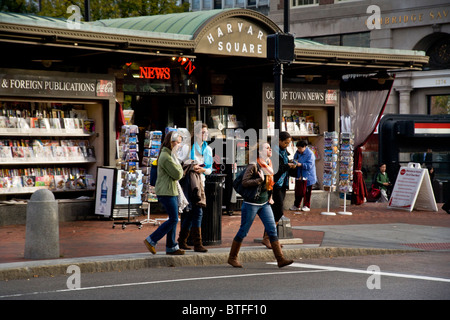 Gli studenti cross Massachusetts Avenue in Harvard Square, Cambridge, MA. Sullo sfondo è la notizia di stand e la stazione della metropolitana. Foto Stock