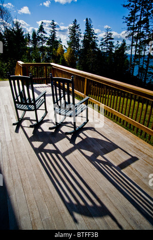 Pomeriggio di sole getta ombre di due sedie a dondolo su una piattaforma in Bernard, Maine Foto Stock