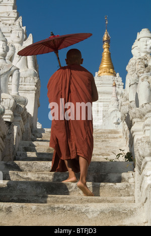 La Pagoda Settawya, giovane monaco buddista con un ombrello rosso salendo le scale, Mingun, birmania, myanmar Foto Stock