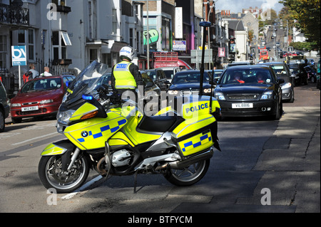 Un motociclista di polizia arresta il traffico prima di marzo sui tagli passa attraverso il centro di Brighton Foto Stock