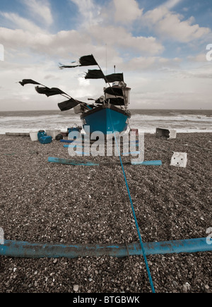 Il turchese barche da pesca sulla spiaggia di Aldeburgh con bandiere nere che fluttua nel vento Foto Stock