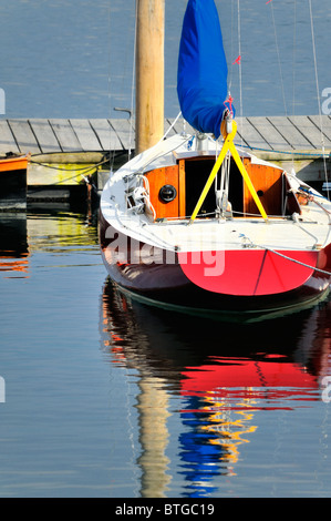 In legno rosso barca a vela ormeggiata al molo, Rockland, Maine, Stati Uniti d'America con riflessi nell'acqua. Foto Stock