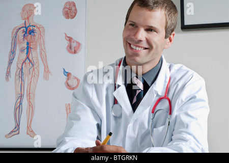 Medico nel suo ufficio con il sistema circolatorio grafico sulla parete Foto Stock