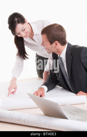Uomo e donna che guarda ai piani a scrivania Foto Stock