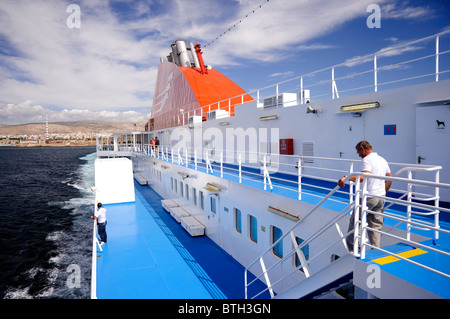 La gente sul ponte di una nave traghetto di lasciare il porto del Pireo per le isole greche. Foto Stock