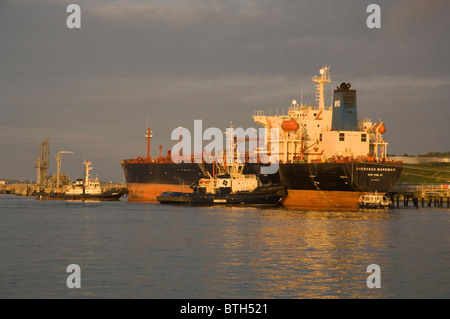 Rimorchiatori spingendo petroliera su jetty, Texaco raffineria di petrolio, Milford Haven, Pembrokeshire, Wales, Regno Unito, Europa Foto Stock