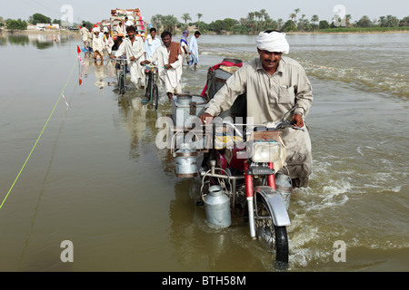 Persone che attraverso strade allagate, Muzaffargarh, Pakistan Foto Stock