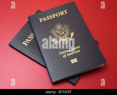 Blu di due Stati Uniti passaporti disposti su una trama fine rosso materiale di sfondo Foto Stock