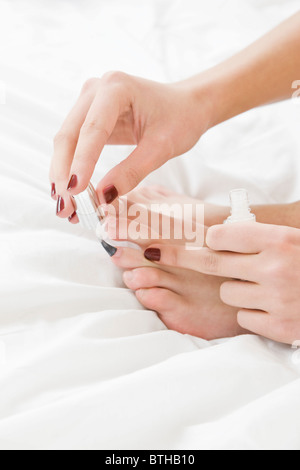 Giovane donna pittura toenails sul letto Foto Stock