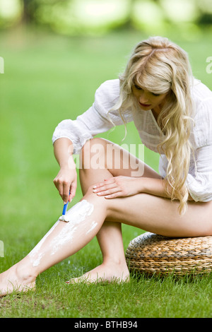 Giovane donna gambe di rasatura in graden Foto Stock