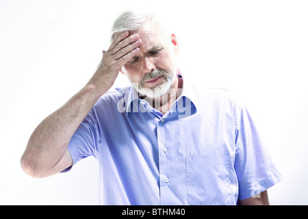 Ritratto su isolati di sfondo bianco di un bel senior espressiva tenendo la sua testa in mano mal di testa di perdita di memoria emicrania Foto Stock