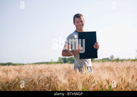 Uomo con pannello solare nel campo di grano Foto Stock