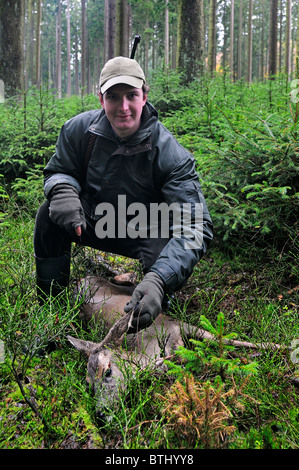 Cacciatore con shot il capriolo (Capreolus capreolus) nella foresta delle Ardenne, Belgio Foto Stock