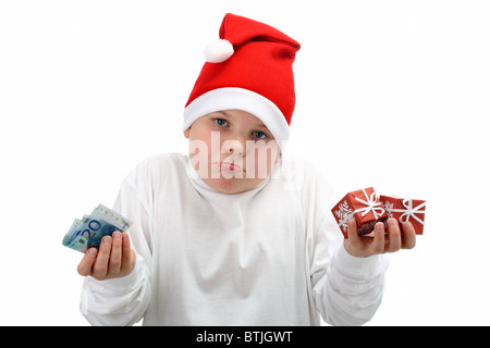 Piccola alzata boy in Santa's Red Hat azienda denaro e regali di Natale isolato su bianco Foto Stock