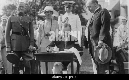 Presidente Calvin Coolidge (1872-33) firma stanziamento fatture per i veterani del Bureau sulla south lawn durante il party in giardino per i veterani feriti nel 1924. La sig.ra Coolidge e il generale John Pershing a guardare. Foto Stock